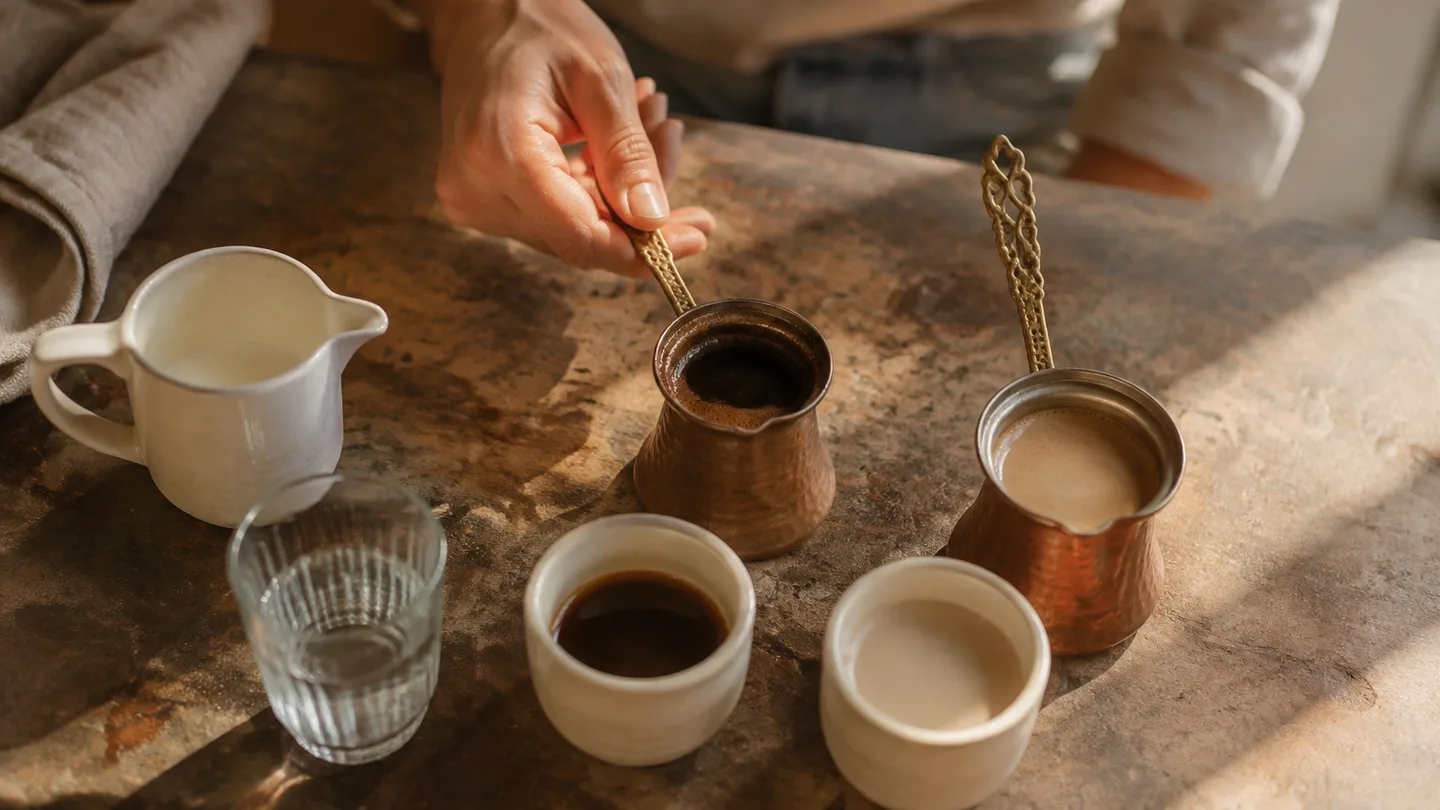A hand compares dark and pale cups with separate water and milk, showing how each liquid changes the drink.