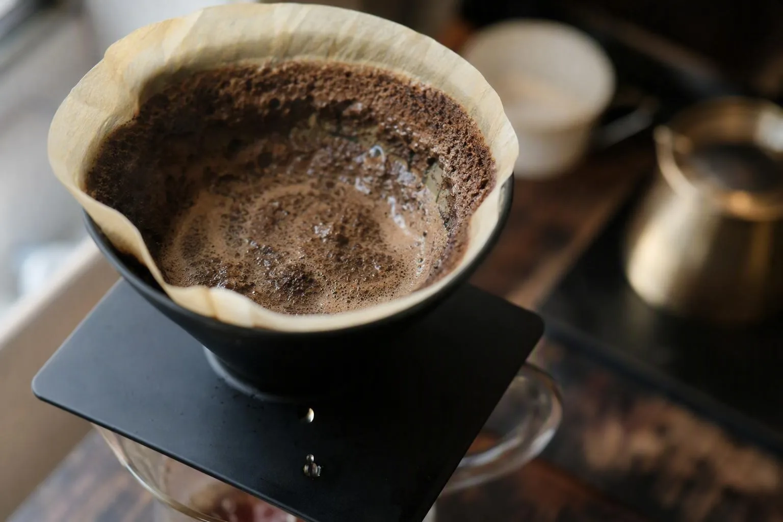 Fine coffee particles cling to a draining filter as water threads through the bed, revealing signs of restricted flow.