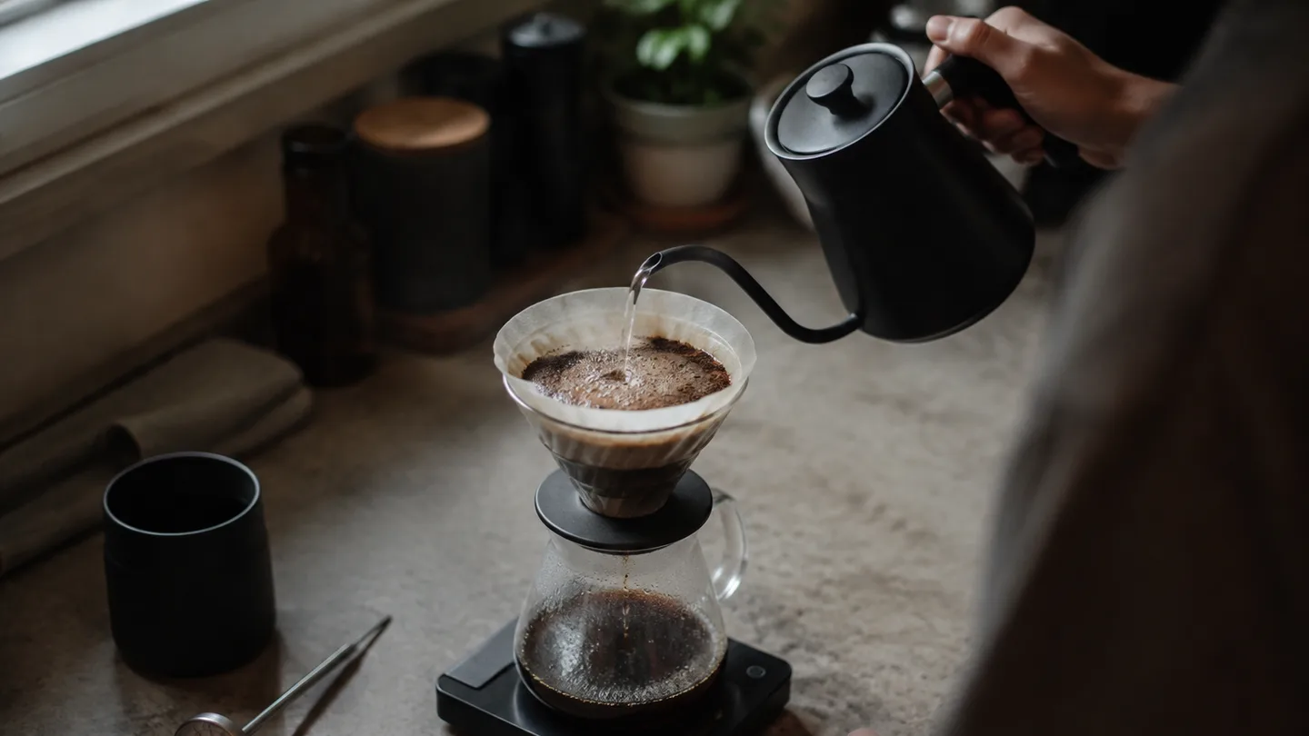 Hot water spreads through freshly wetted coffee grounds as a thermometer checks the brew beside the brewer.